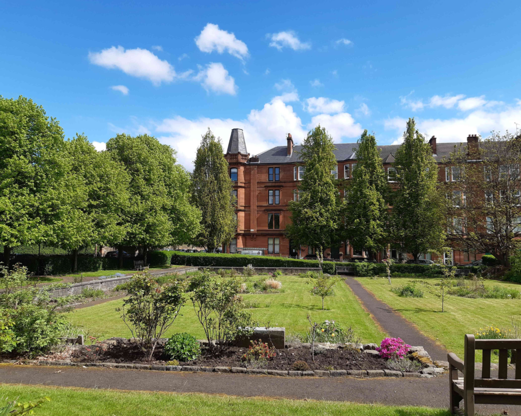 A garden with brick buildings in the background