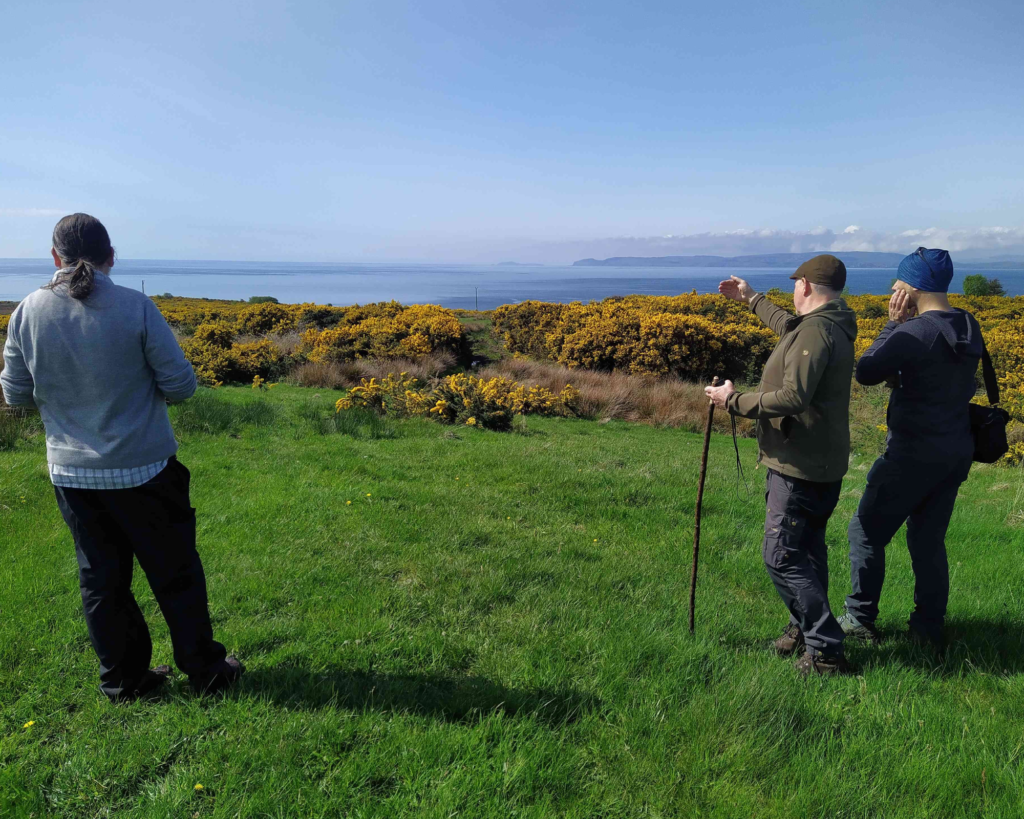 Three people looking at the horizon where the sea is visible